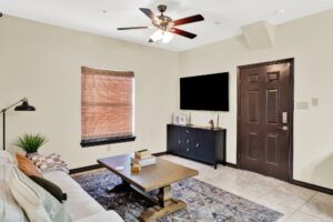 A bright living room with a soft couch, a contemporary coffee table, and a large television for entertainment at La Joya Apartments in Laredo, Texas