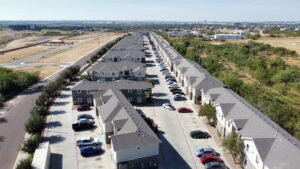 La Joya Apartments External Aerial Photo - Aerial perspective of La Joya Apartments, featuring a neighborhood with vehicles parked in residential driveways