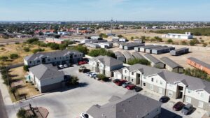 Overhead perspective of La Joya Apartments, a residential area, highlighting homes and parking lots amidst tree-lined streets and open spaces