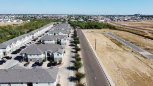 Overhead perspective of La Joya Apartments, a suburban area featuring homes, roads, and landscaped gardens in a residential setting