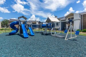 Outdoor children's playground at Edgewater Pointe Apartments in Biloxi, MS, with play structures and grassy area