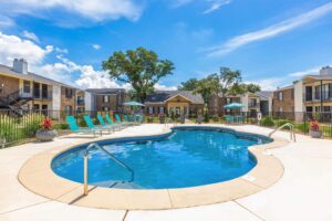Outdoor swimming pool at Edgewater Pointe Apartments in Biloxi, MS, with seating and lush surroundings