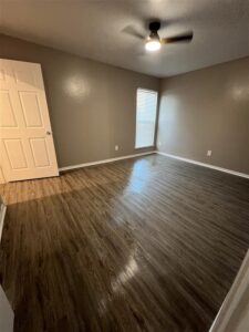 Spacious 3 bedroom apartment interior at Trailwood Village in Kingwood, TX featuring wood-style flooring and modern ceiling fan.