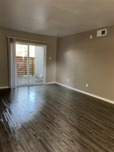 Spacious bedroom in a 3-bedroom Abberly unit at Trailwood Village Apartments featuring wood-style flooring and a built-in closet organization system.