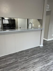 Renovated kitchen at Trailwood Village Apartments in Kingwood, TX, showcasing granite-style countertops, a breakfast bar, and stainless steel appliances.