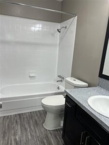 Modern bathroom in a 3-bedroom apartment at Trailwood Village in Kingwood, TX, featuring dark wood cabinetry and a white tile tub surround.