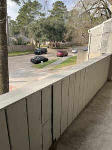 Private apartment balcony at Trailwood Village Apartments overlooking a tree-lined street in the Kingwood "Livable Forest" area.