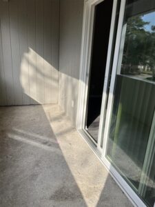 Private apartment balcony at Trailwood Village featuring a concrete patio floor, neutral siding, and a large sliding glass door.