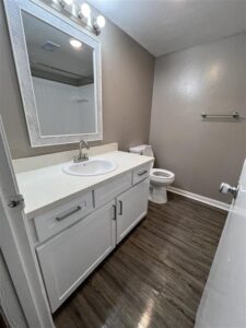 Modern bathroom in a 3-bedroom apartment at Trailwood Village in Kingwood, TX, featuring white cabinetry, quartz-style countertops, and wood-plank flooring.