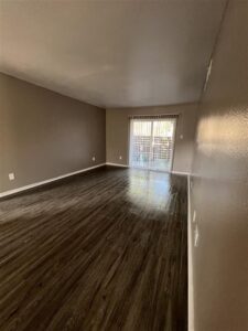 Bedroom in a 3-bedroom Abberly unit at Trailwood Village Apartments featuring wood-style flooring and a built-in closet organization system.
