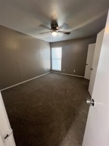 View of a modern master bathroom with a white vanity, framed mirror, and wood-style flooring in a renovated unit at Trailwood Village Apartments in Kingwood, Texas.