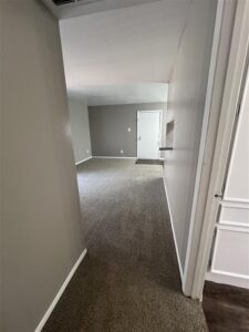 View from a hallway looking into a modern, open-concept living room and entryway at Trailwood Village Apartments in Kingwood, Texas.