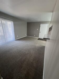 Wide-angle view of an open-concept living room at Trailwood Village Apartments in Kingwood, TX, featuring a granite-style breakfast bar, plush carpeting, and private entry.