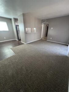 Wide-angle view of a spacious, open-concept living, dining, and kitchen area in a renovated apartment at Trailwood Village in Kingwood, TX.