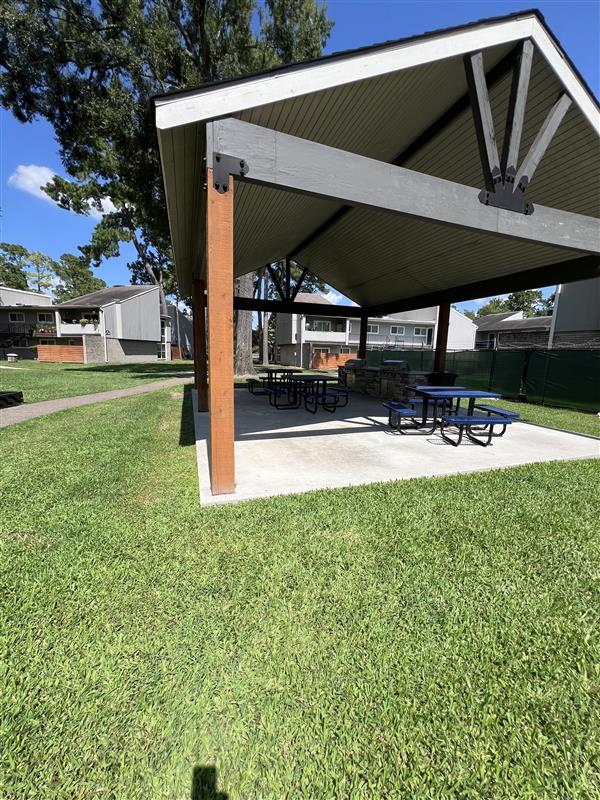 BBQ area at Trailwood Village Apartments in Kingwood, TX, with a gazebo and picnic tables set for outdoor picnics